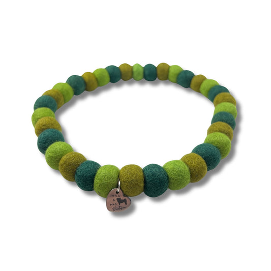 Dog pom pom necklace made of different shades of green wool felt balls.