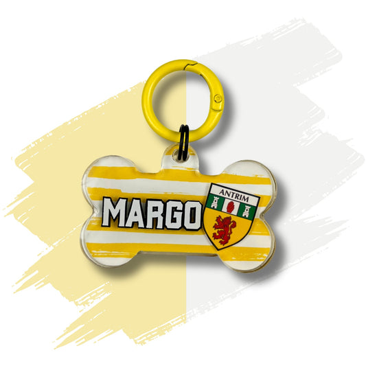 Antrim dog ID tag – handmade resin bone-shaped name tag with white and yellow stripes, Antrim crest, and custom pet name, part of the Northern Irish County Collection by Mylo and Mas Boutique.